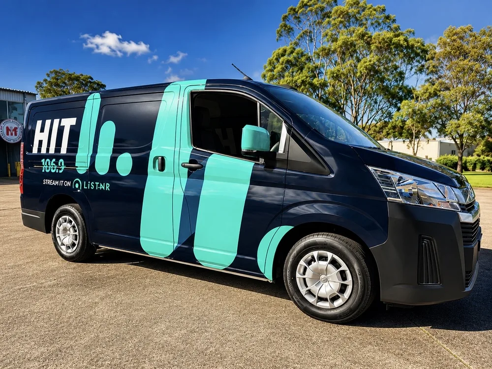 Hit 106.9 van in a dark navy and mint green printed wrap