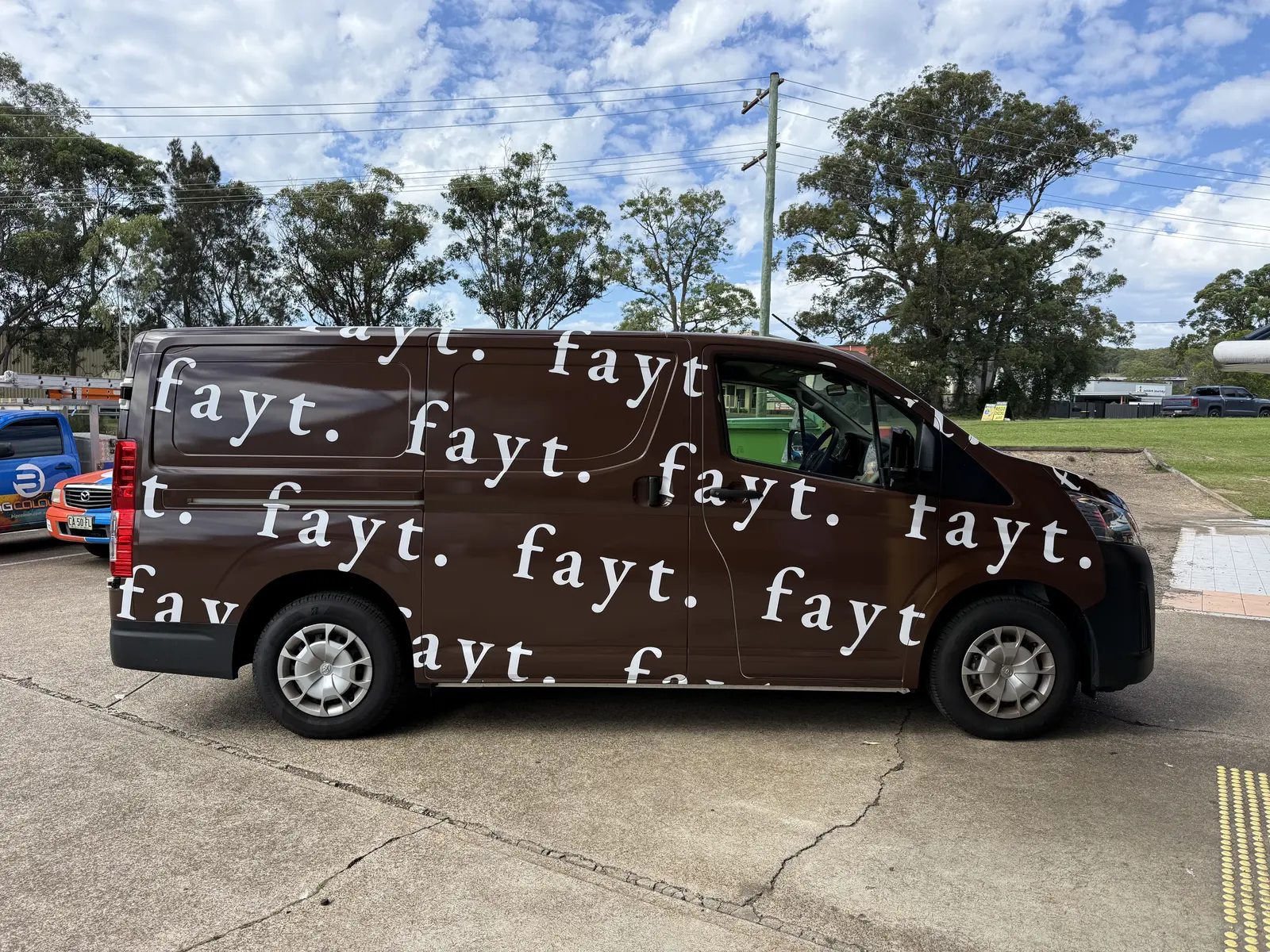 FAYT The Label, Side of the chocolate-brown FAYT van with the white fayt. logotype repeating across its panels