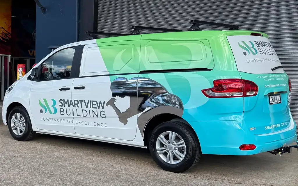 Smartview Building van wrapped in a green and white design, parked in front of an industrial corrugated metal building.