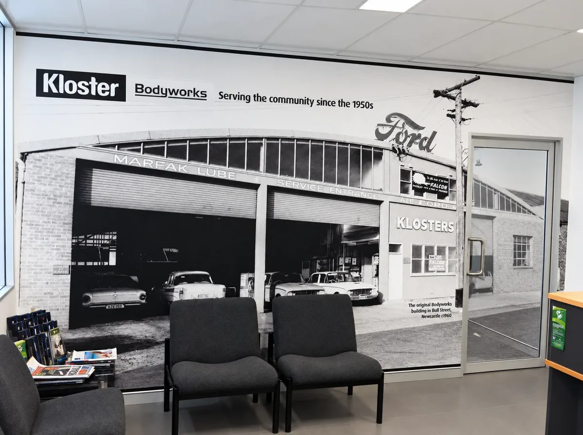 Kloster Bodyworks reception wall mural in Wickham, showing a historic black and white photograph of the original Bodyworks building with the Kloster Bodyworks logo