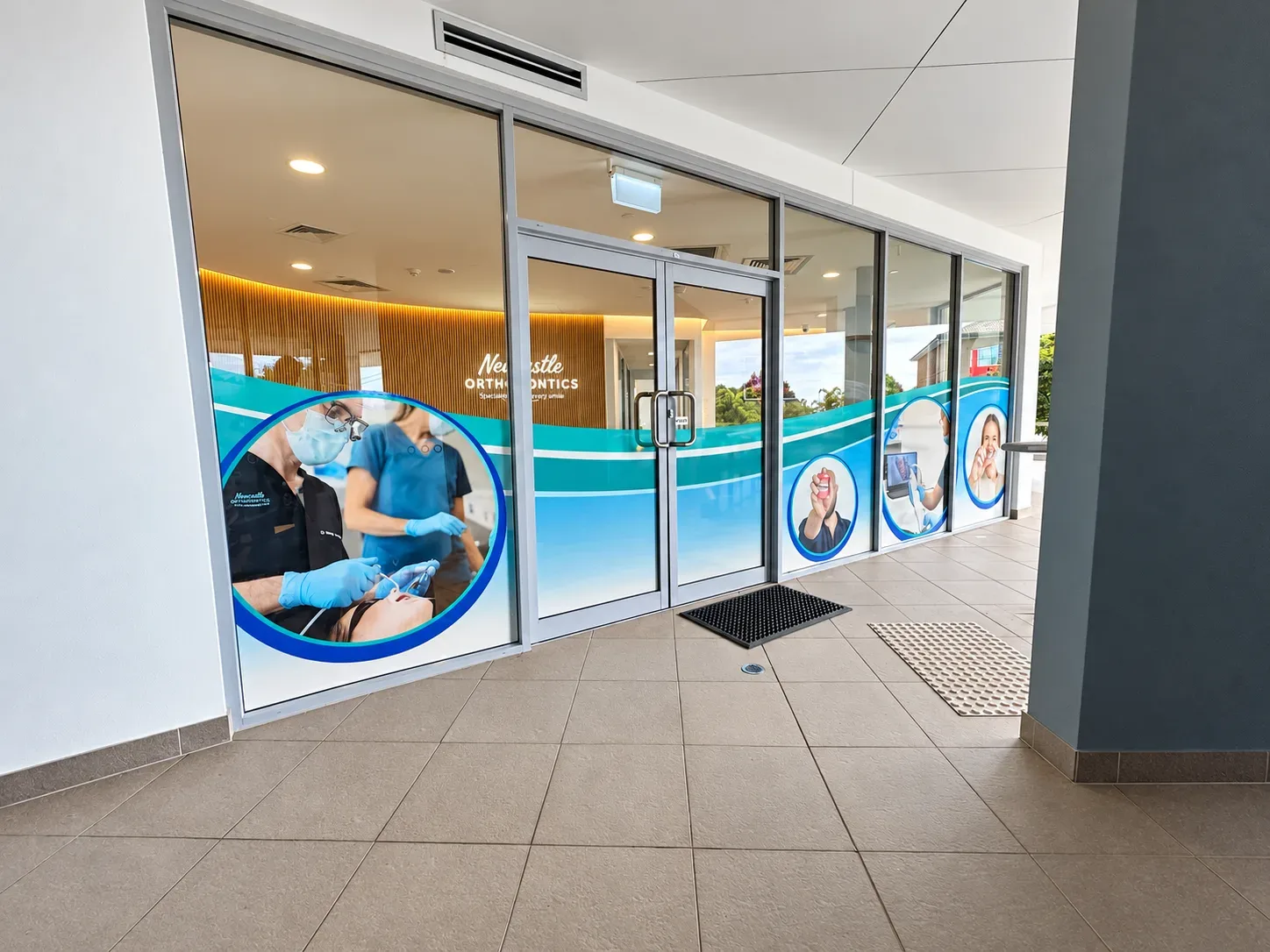 Newcastle Orthodontics entrance in Charlestown with full-colour one-way vision graphics on the glass doors and windows