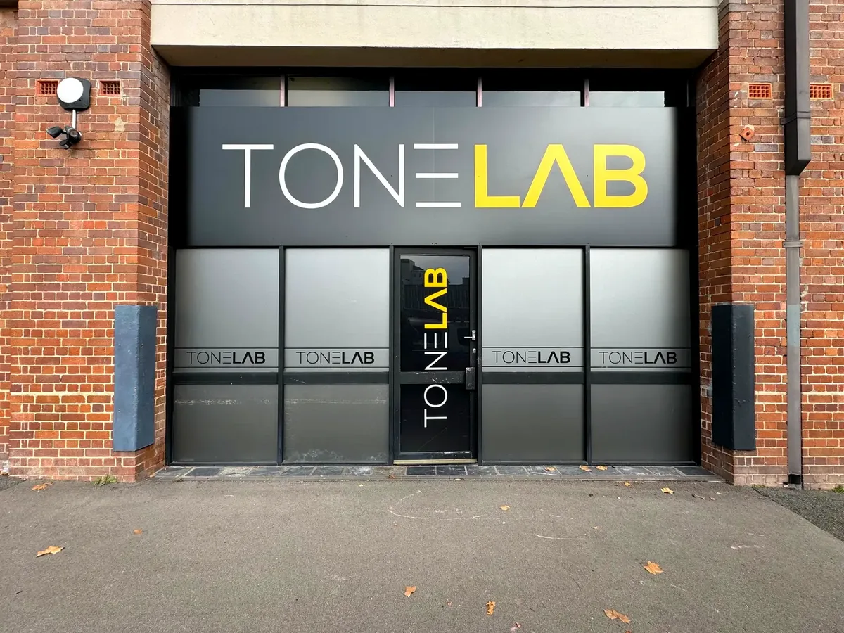 ToneLAB Training shopfront in Newcastle West: a charcoal fascia sign with TONE in white and LAB in yellow, frosted window film repeating the TONELAB logo and a black door lettered vertically, set in a red-brick facade