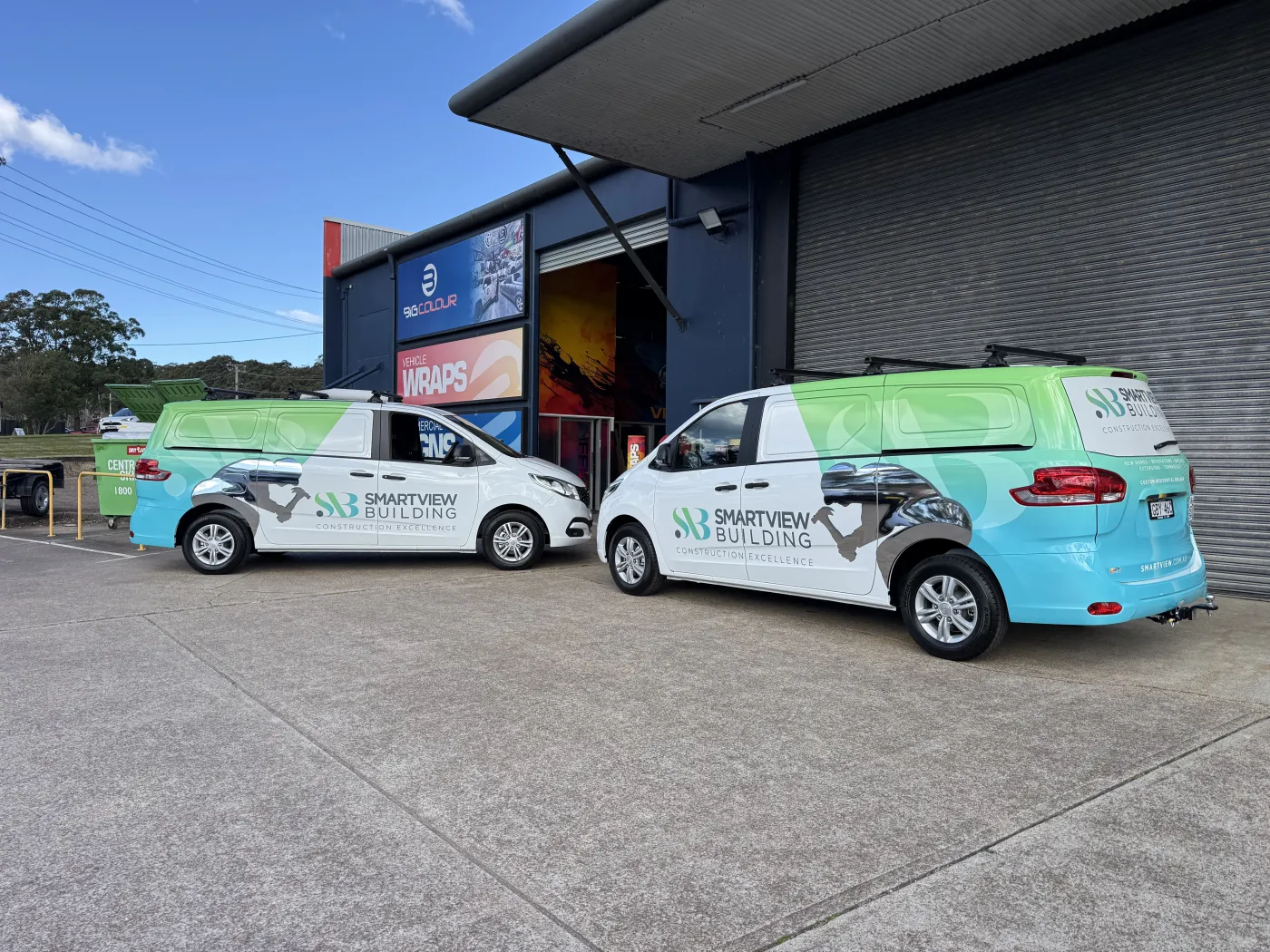 Two Smartview Building vans in green and aqua full wraps outside the workshop