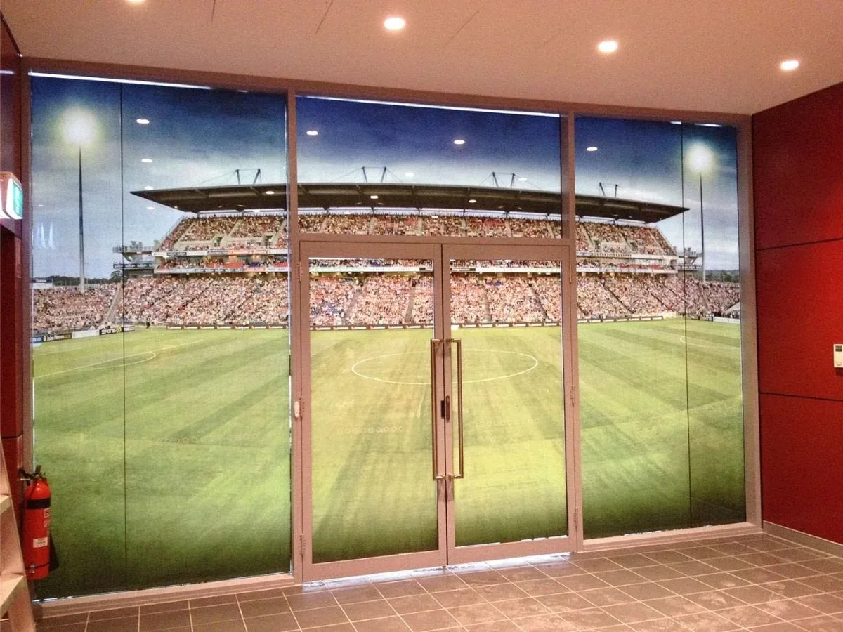 Full-colour stadium crowd and pitch photo printed across an internal glass wall and double doors