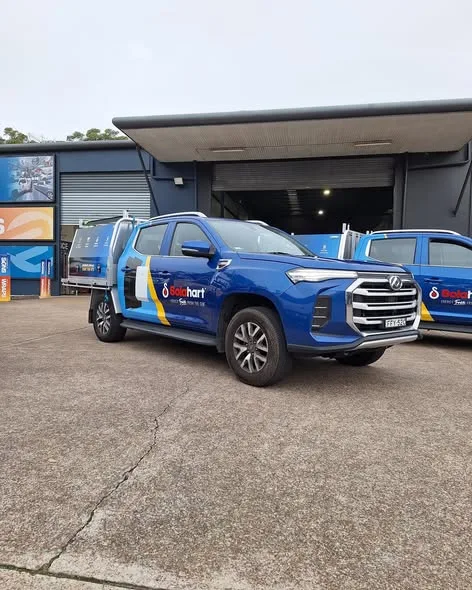 Single blue Solahart ute front three-quarter, tray fitted, the red-drop logo and energy-from-the-sun line on the door