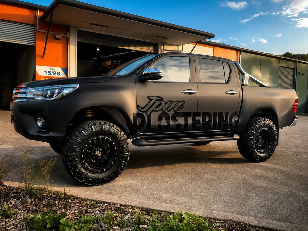 JPW Plastering Hilux ute in a matte black wrap with gloss black lettering