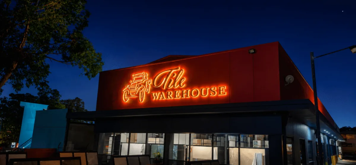 Tile Warehouse illuminated neon-style sign at dusk