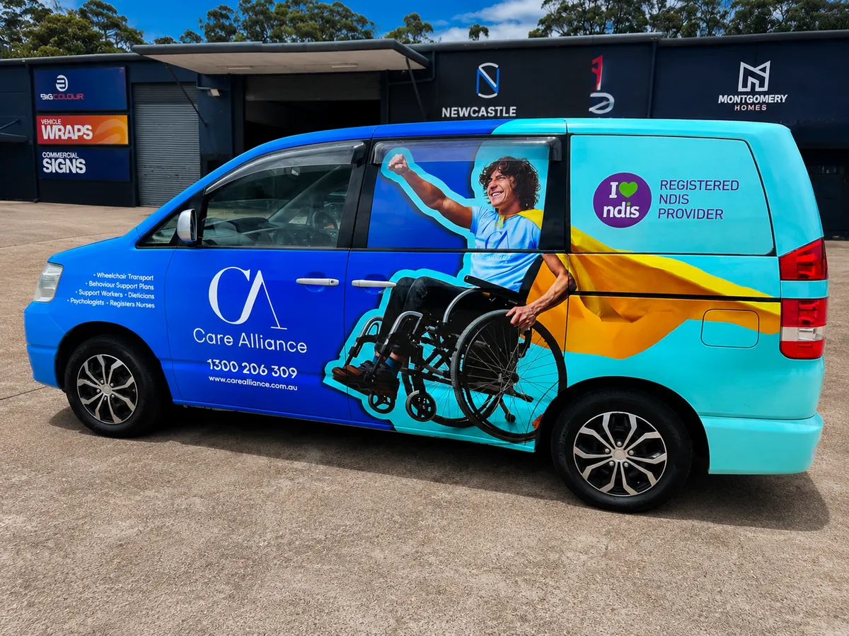 Care Alliance van in the blue and aqua wrap with the wheelchair user graphic